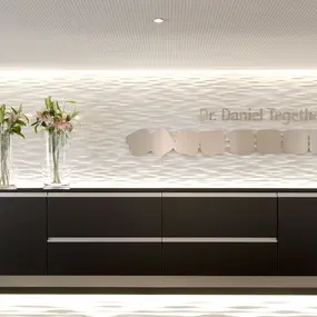 Moderner Empfangsbereich einer Zahnarztpraxis mit stilvoller Einrichtung und Blumendekoration.