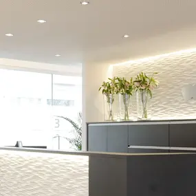 Modernes, helles Zahnarztpraxis-Empfangsbereich mit stilvoller Einrichtung und Blumendekoration.